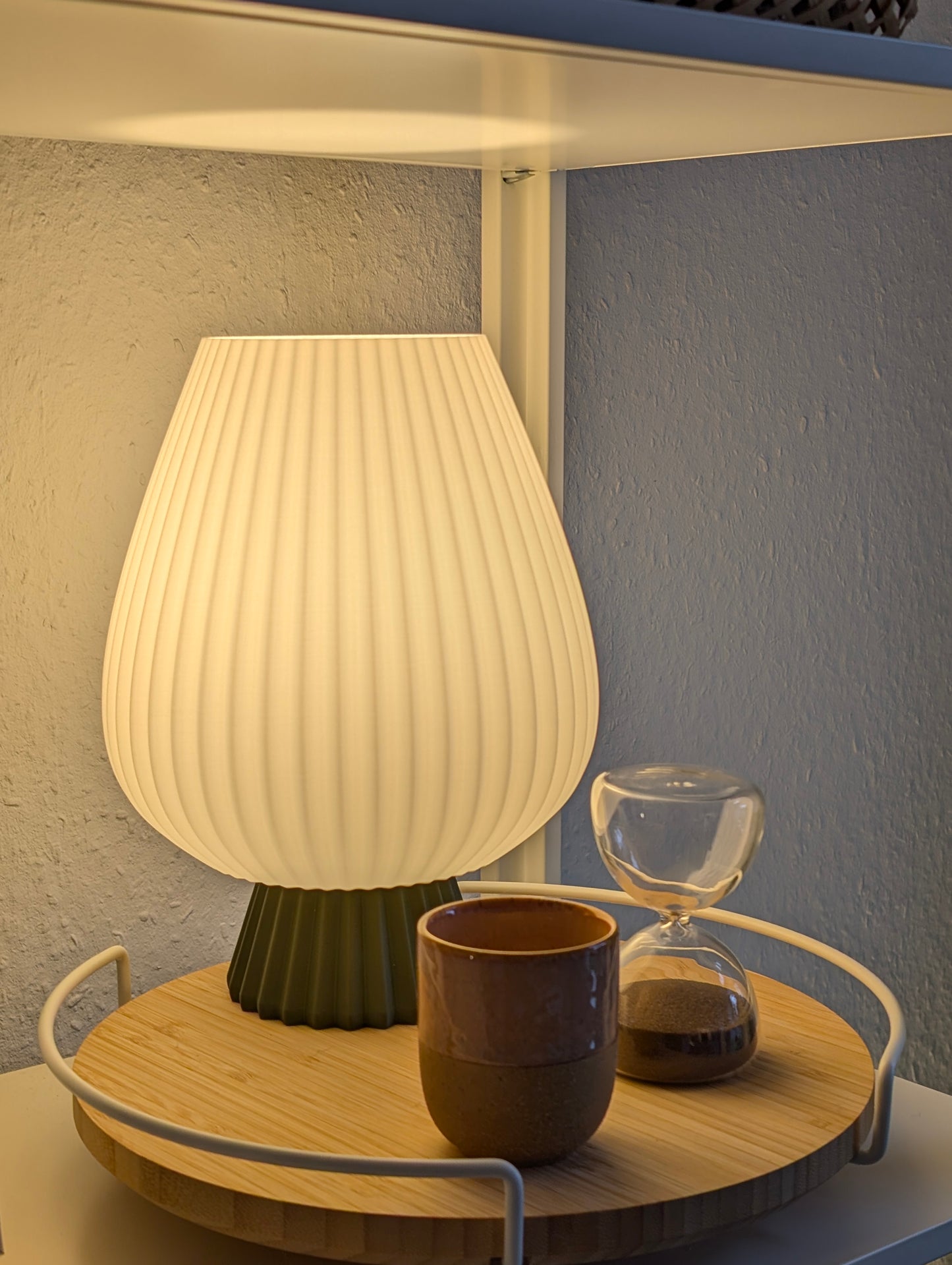 Fluted table lamp with rounded shape and soft diffused light on a bedside table