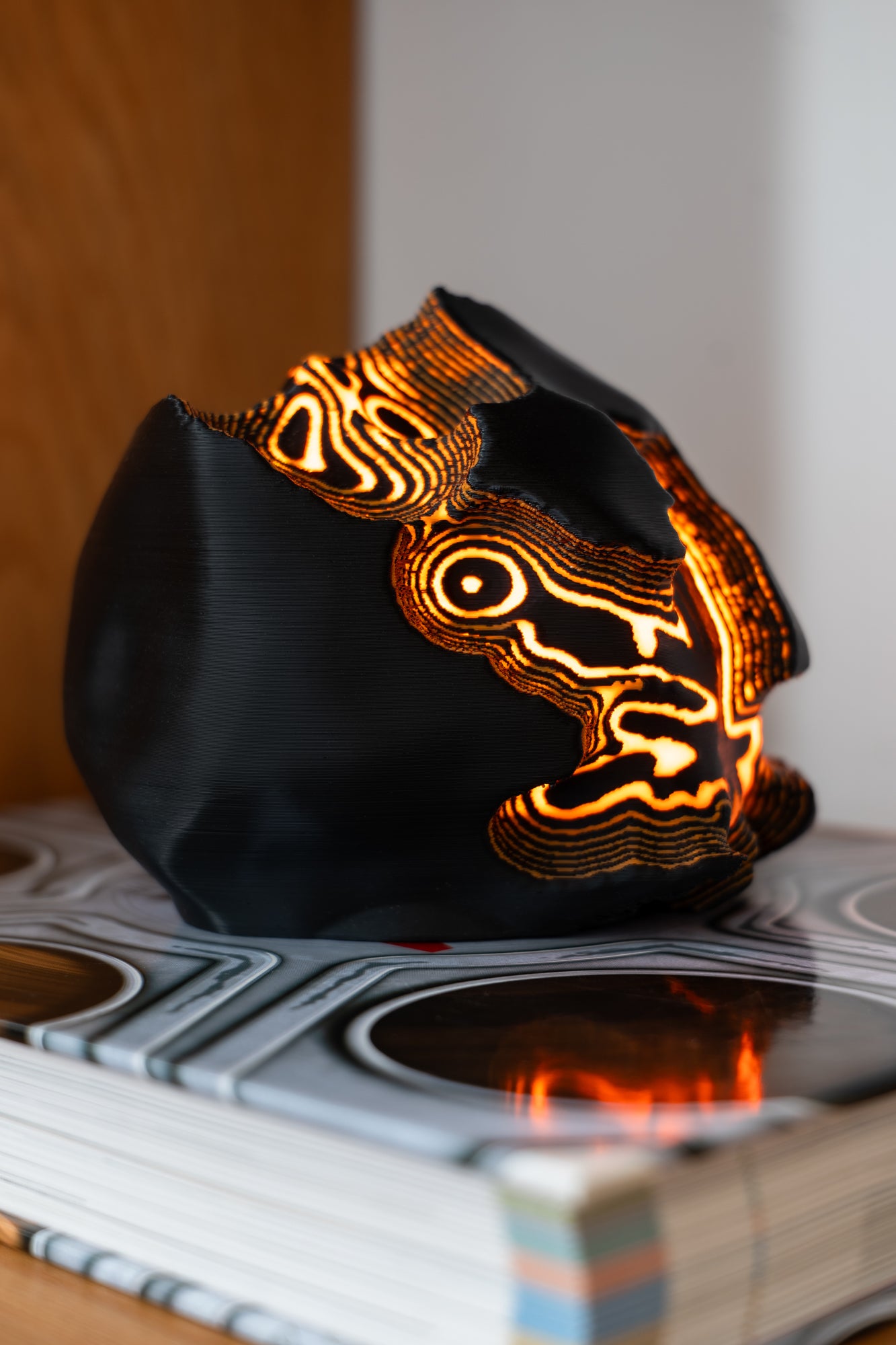 Black lamp with glowing orange patterns on a book