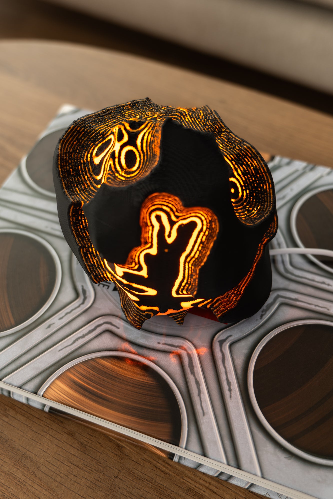 Decorative lamp with glowing orange design on a textured surface