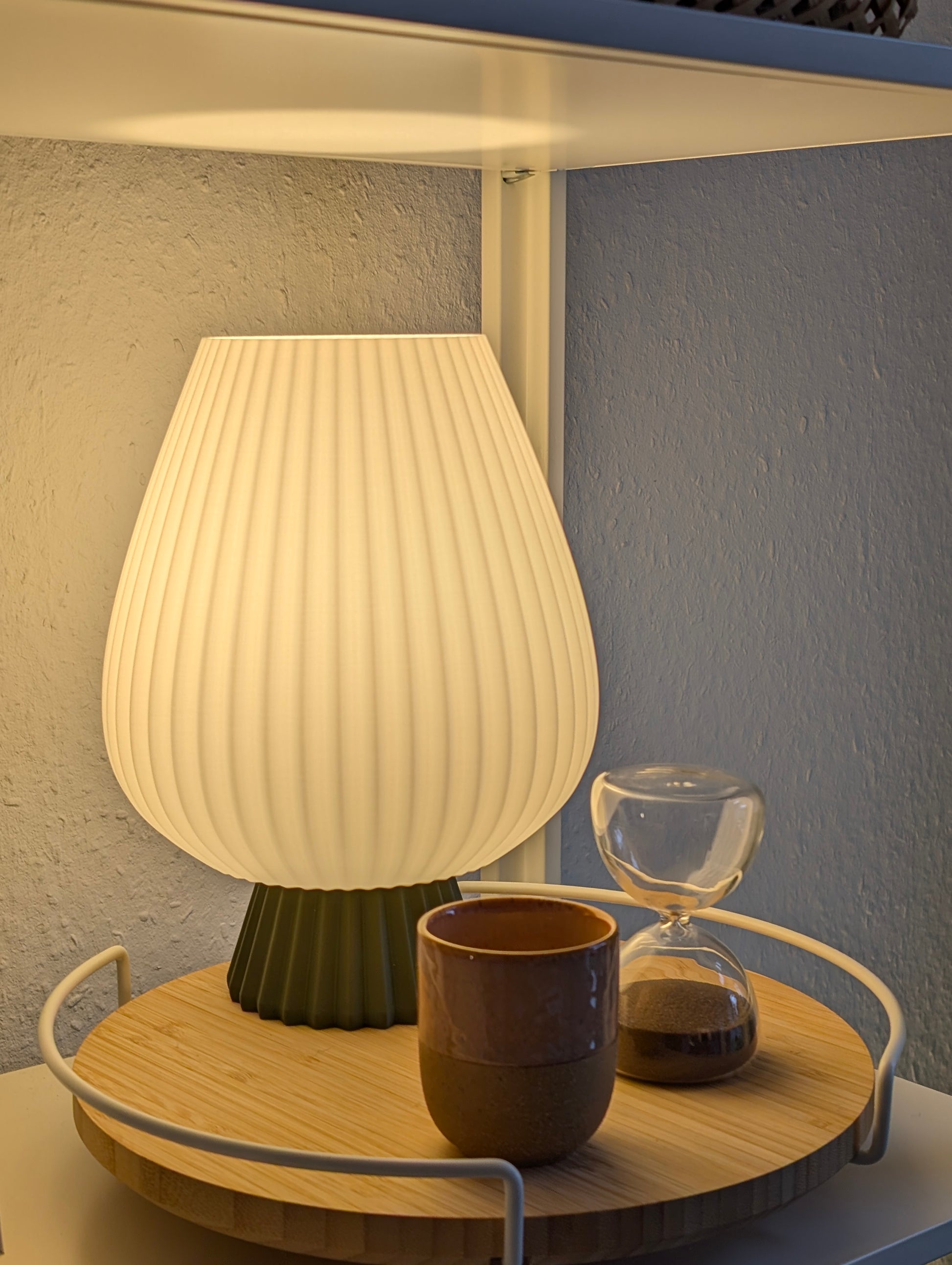 Fluted table lamp with rounded shape and soft diffused light on a bedside table