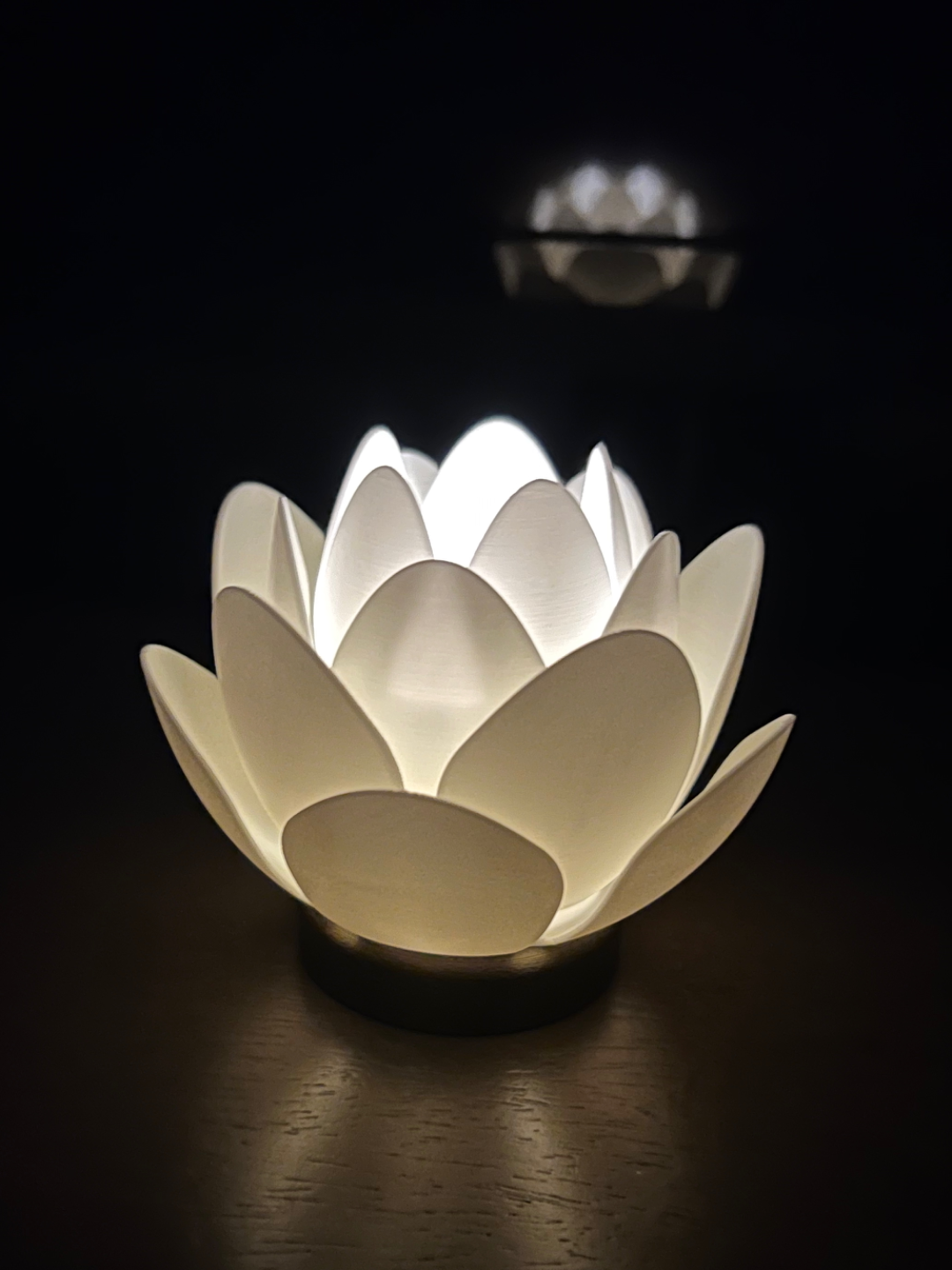 Lotus flower tea light holder with layered petals glowing softly on a dark background