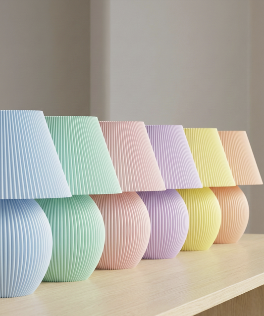 Pleated table lamp with rounded base in multiple pastel colours arranged in a row