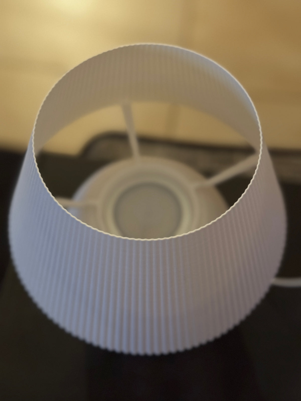White lampshade on a dark surface with a blurred background
