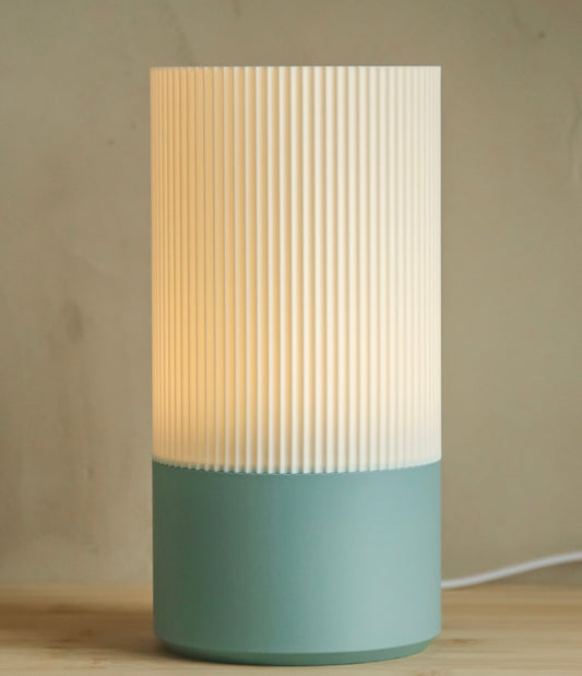 Ribbed cylindrical table lamp emitting a soft warm glow with a minimal modern design