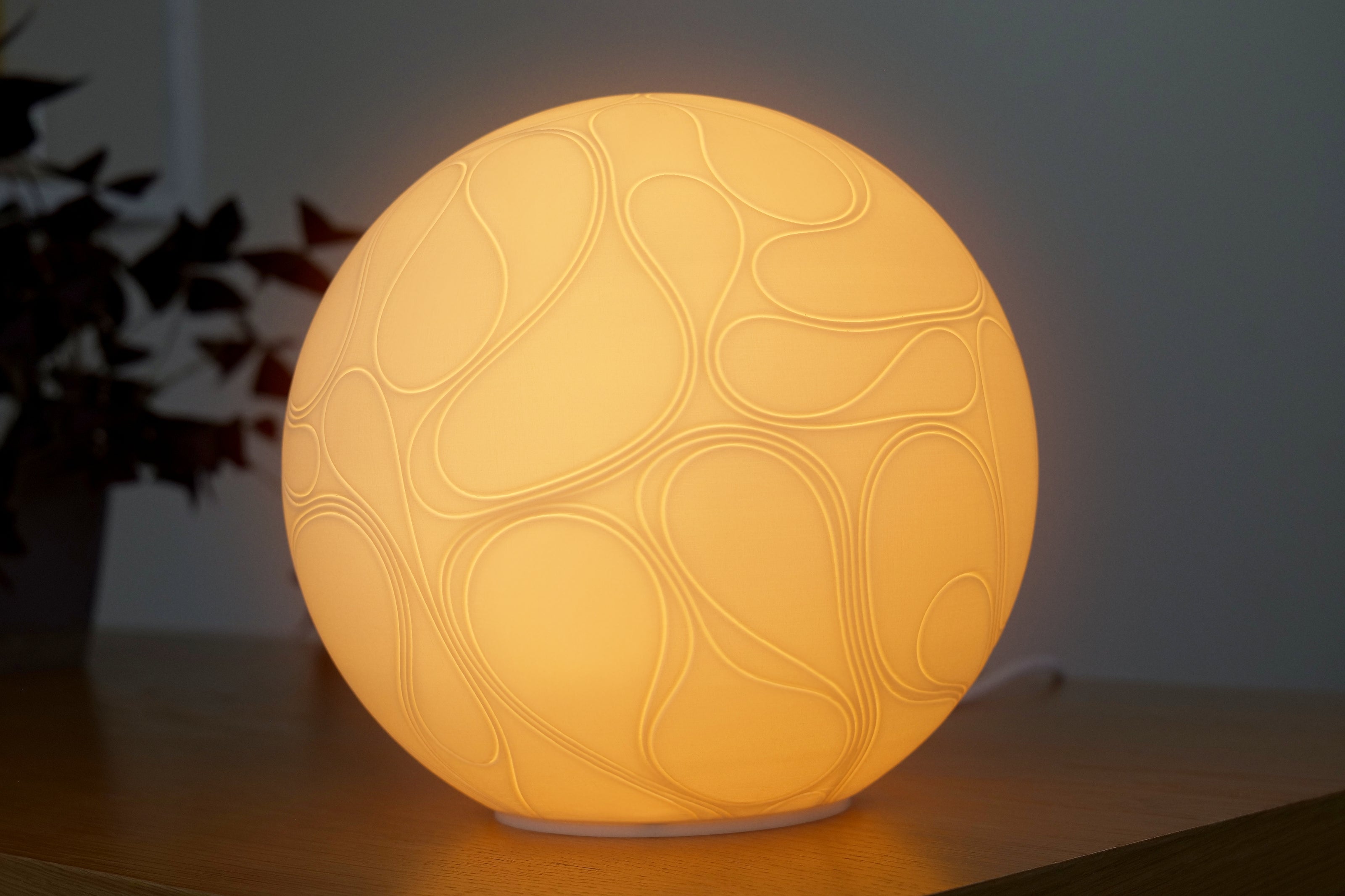 Round lamp with embossed design on a wooden surface
